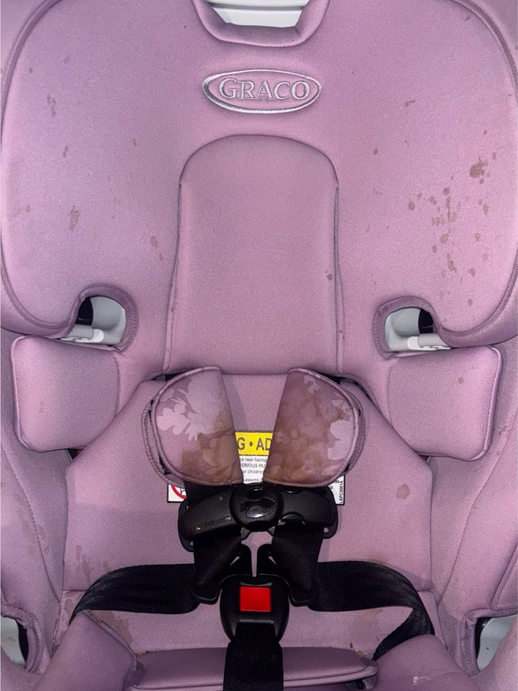 Pink Graco car seat before cleaning, with stains on the cover and harness pads